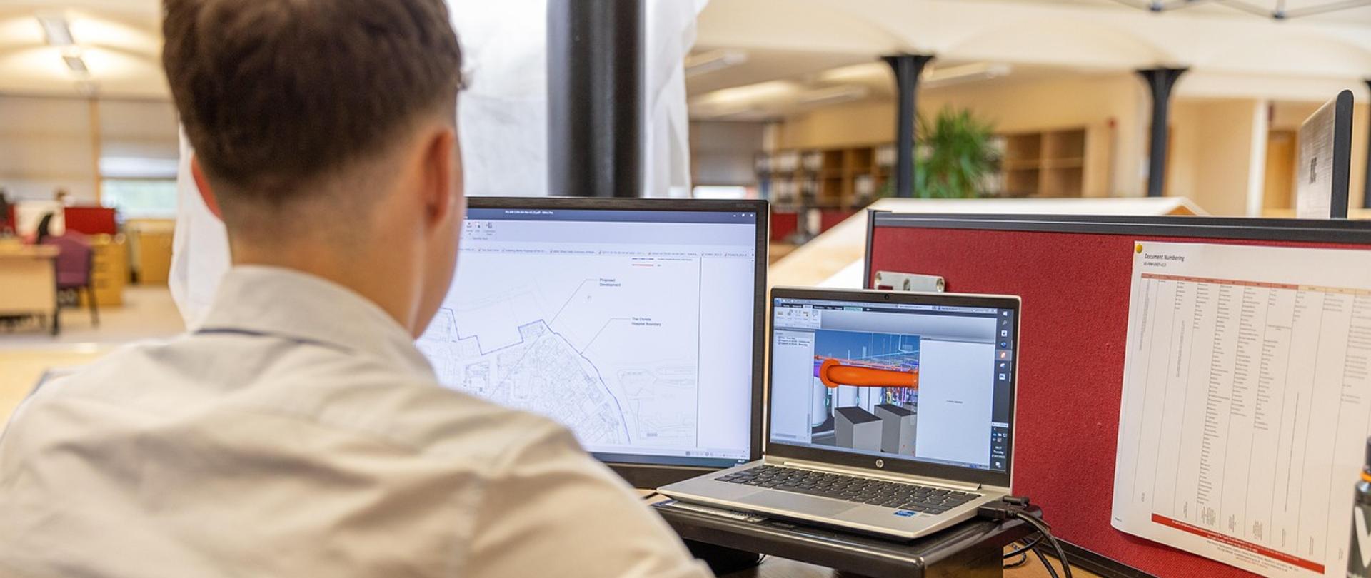 Inżynier przy biurku przed monitorami