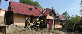 Strażacy prowadzą działania gaśnicze z dachu.
