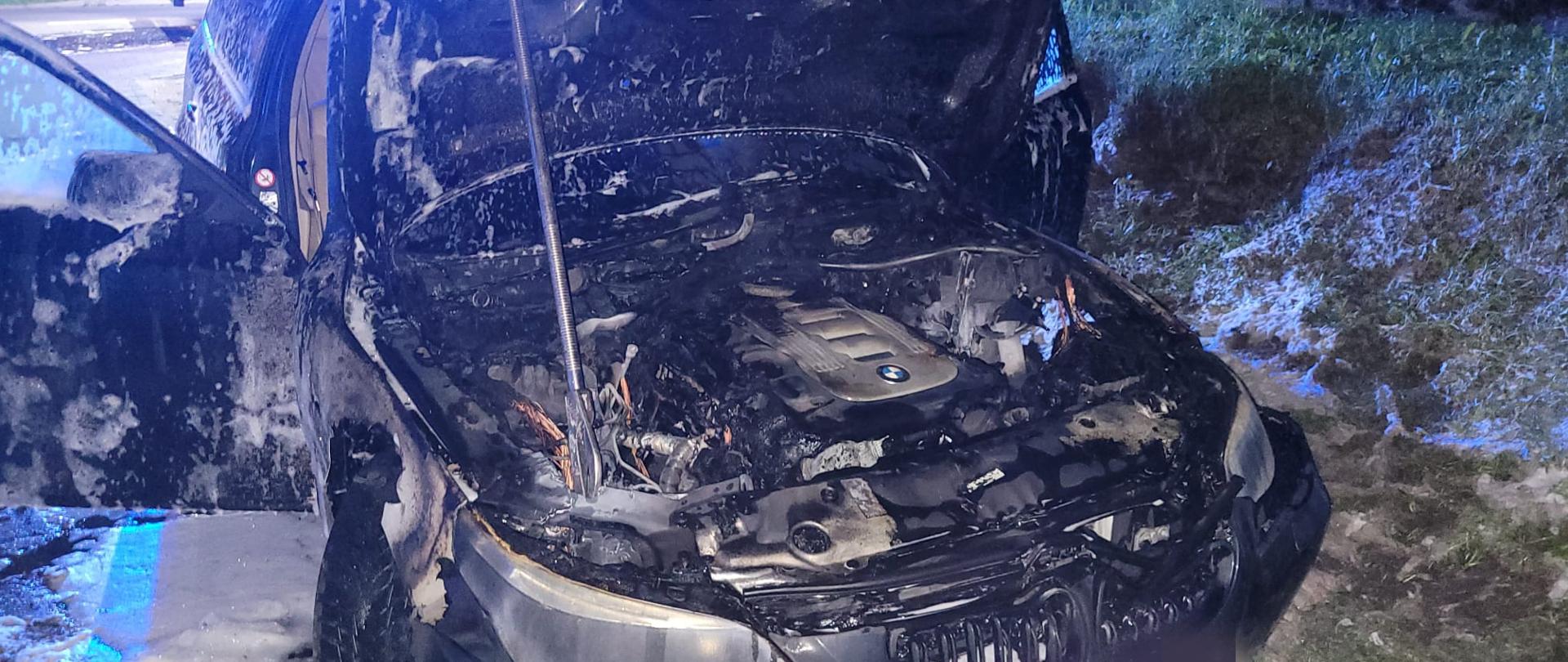 Auto marki BMW stojące na trawie z otworzoną maską.