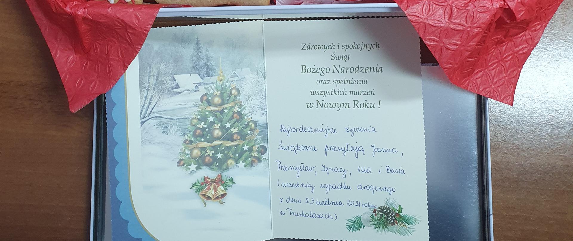 Zdjęcie przedstawia pudełko z piernikami oraz kartę Świąteczną z życzeniami dla strażaków