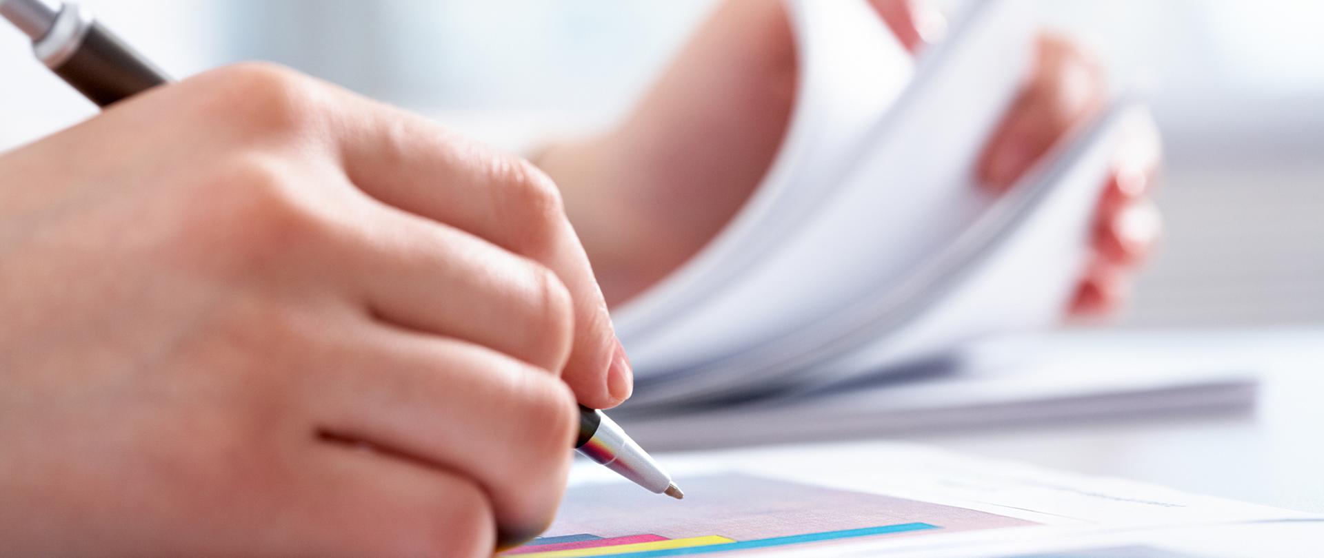 Close-up of female hand holding pen over business graph 