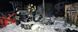 Jest noc, widać strażaków jak gaszą pożar opon i kombajn