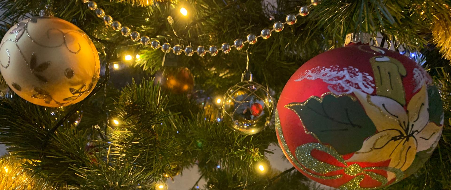 Zdjęcie przedstawiające fragment ubranej w bombki i kolorowe lampki choinki 