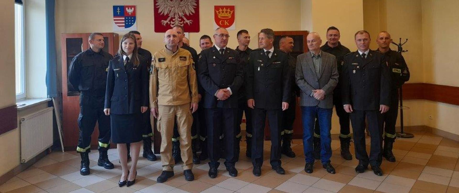 Zdjęcie przedstawia osoby zebrane na uroczystości pożegnania odchodzącego emeryta w sali świetlicowej Jednostki Ratowniczo-Gaśniczej Numer 3 w Kielcach.