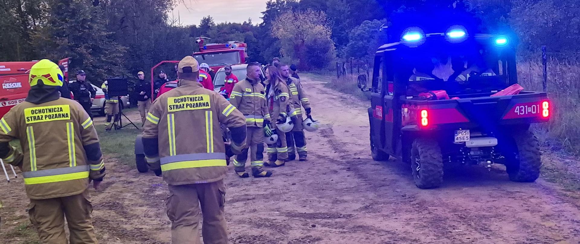 Zdjęcie przedstawia strażaków oraz pojazd quad typu UTV.