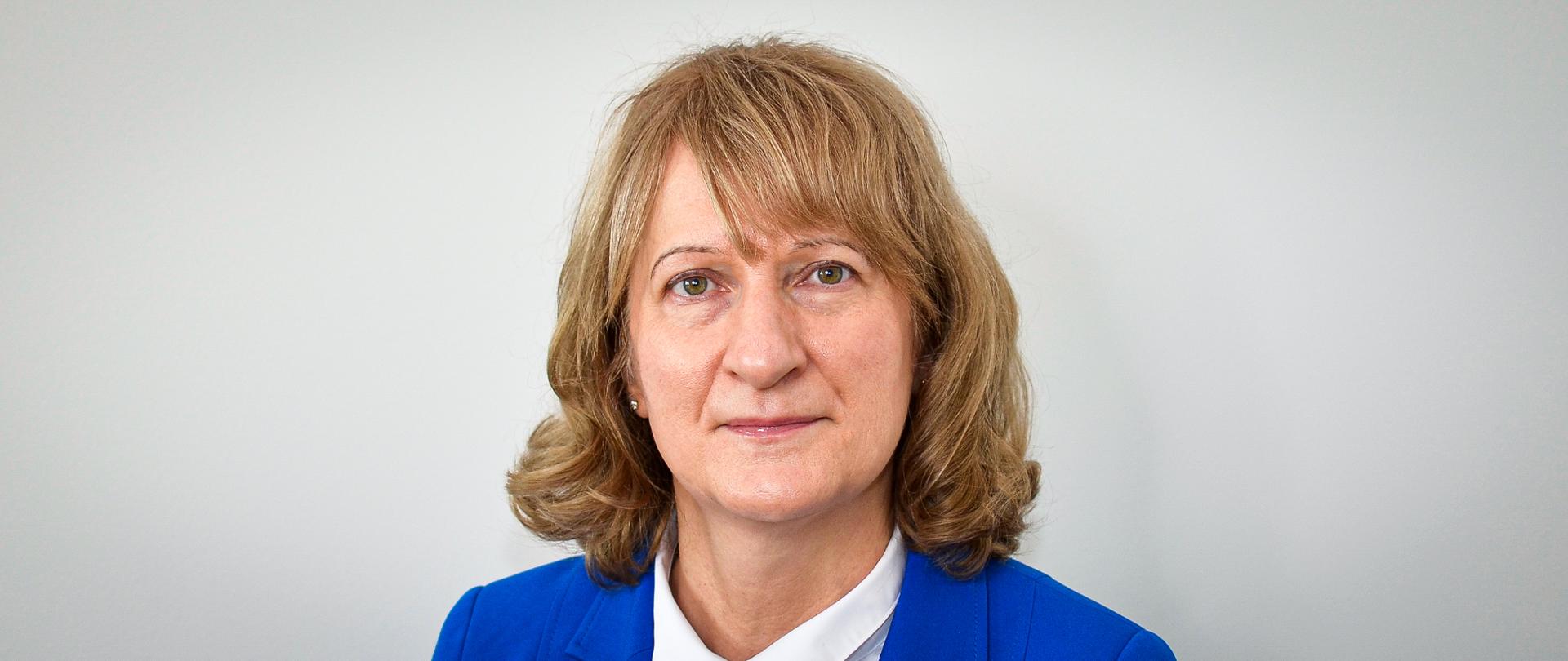 Kobieta w chabrowej marynarce i białej bluzce, z włosami do ramion 