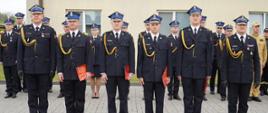 Czterej awansowani funkcjonariusze Państwowej Straży pożarnej stoją w rzędzie na placu jednostki ratowniczo-gaśniczej i trzymają w rękach przyznane awanse. Po ich lewej stronie stoi komendant powiatowy Państwowej Straży Pożarnej w Rypinie, a po prawej Kujawsko-pomorski Komendant Wojewódzki Państwowej Straży Pożarnej.