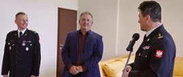 Od lewej strony stojący Zastępca Komendanta Centralnej Szkoły PSP, mężczyzna oraz Komendant Centralnej Szkoły PSP przemawiający do mikrofonu