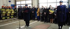 Widok z przodu. Komendant powiatowy PSP w Wadowicach wita uczestników uroczystości. Po prawej stronie stoi oficer PSP - dowódca uroczystości. W tle widoczni zaproszeni goście.