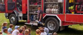Strażak demonstruje dzieciom sposób działania sprzętu strażackiego