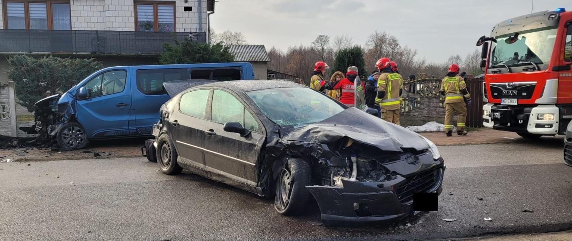 samochody po zderzeniu na ulicy, w tle dom mieszkalny samochód pożarniczy, strażacy