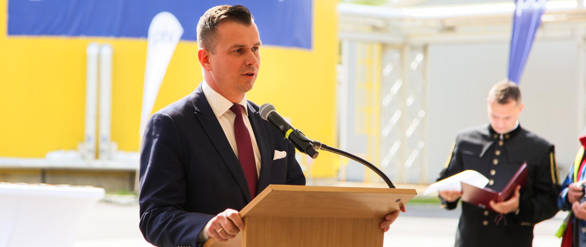 Wiceminister Adam Hamryszczak przemawia w mównicy do mikrofonu