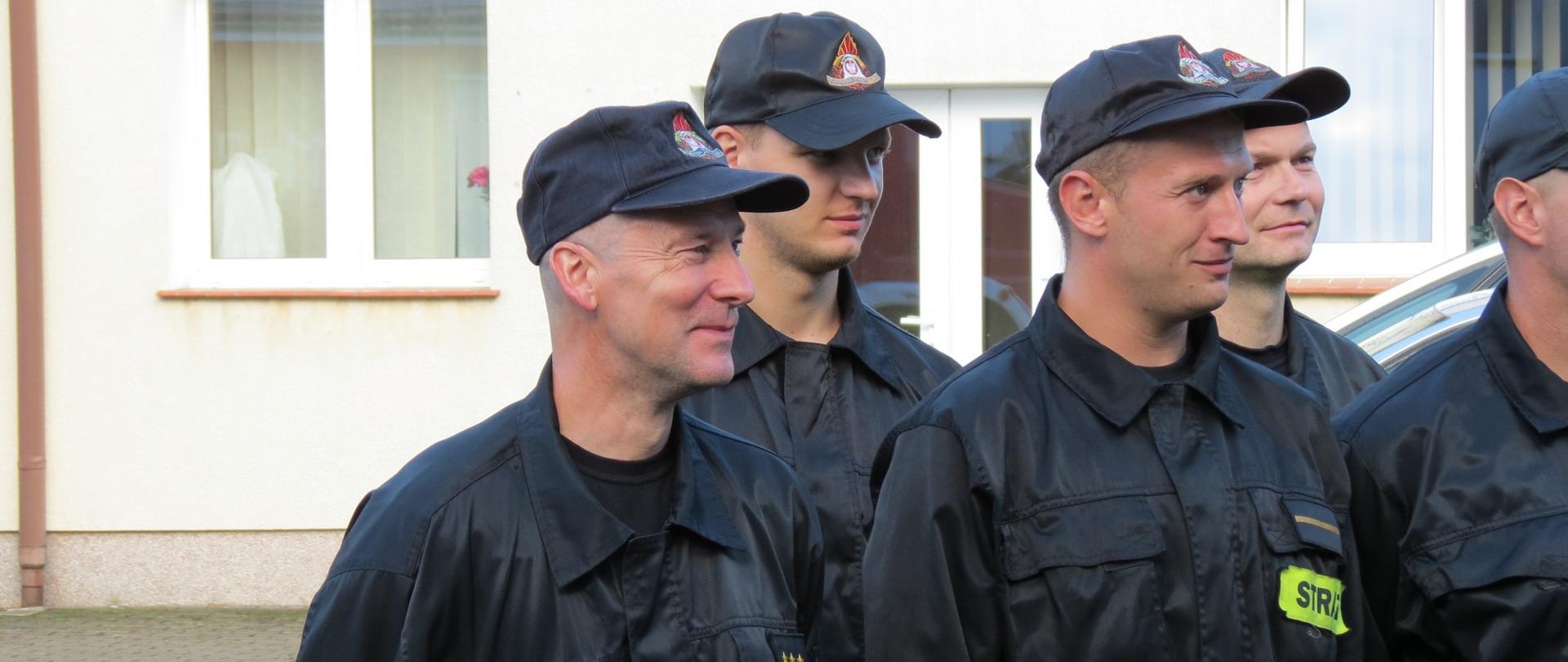 Zdjęcie przedstawia uśmiechniętego asp. sztab. Jacka Lewandowskiego w otoczeniu kolegów ze zmiany służbowej.