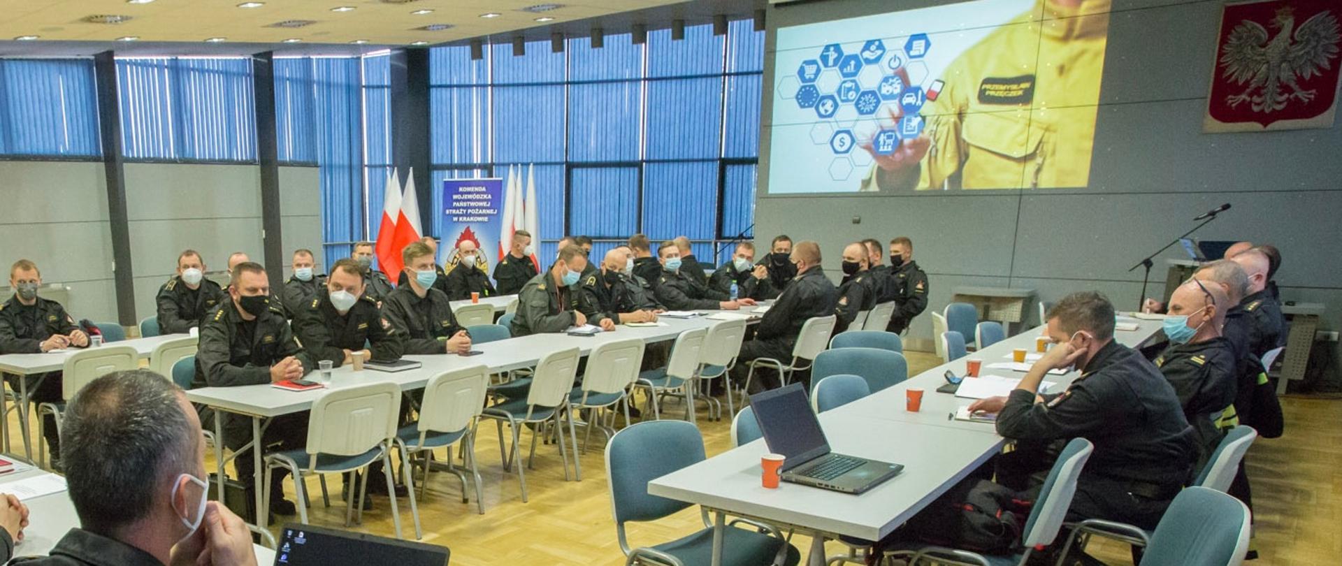 Osoby siedzą za stolikami w czasie narady 