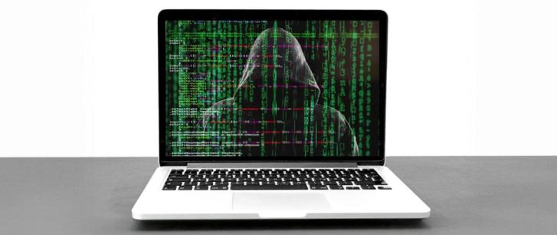Otwarty laptop. Na ekranie zakapturzona ciemna postać.