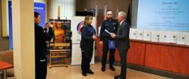 Policjant i policjantka wręczają podziękowanie wykładowcy.