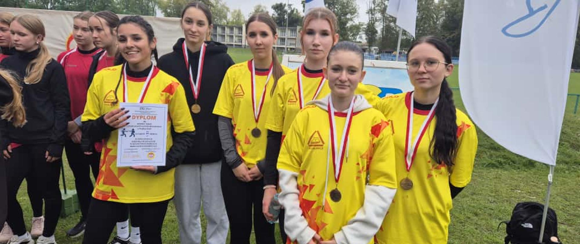 Dziewczęta prezentują medale na tle stadionu