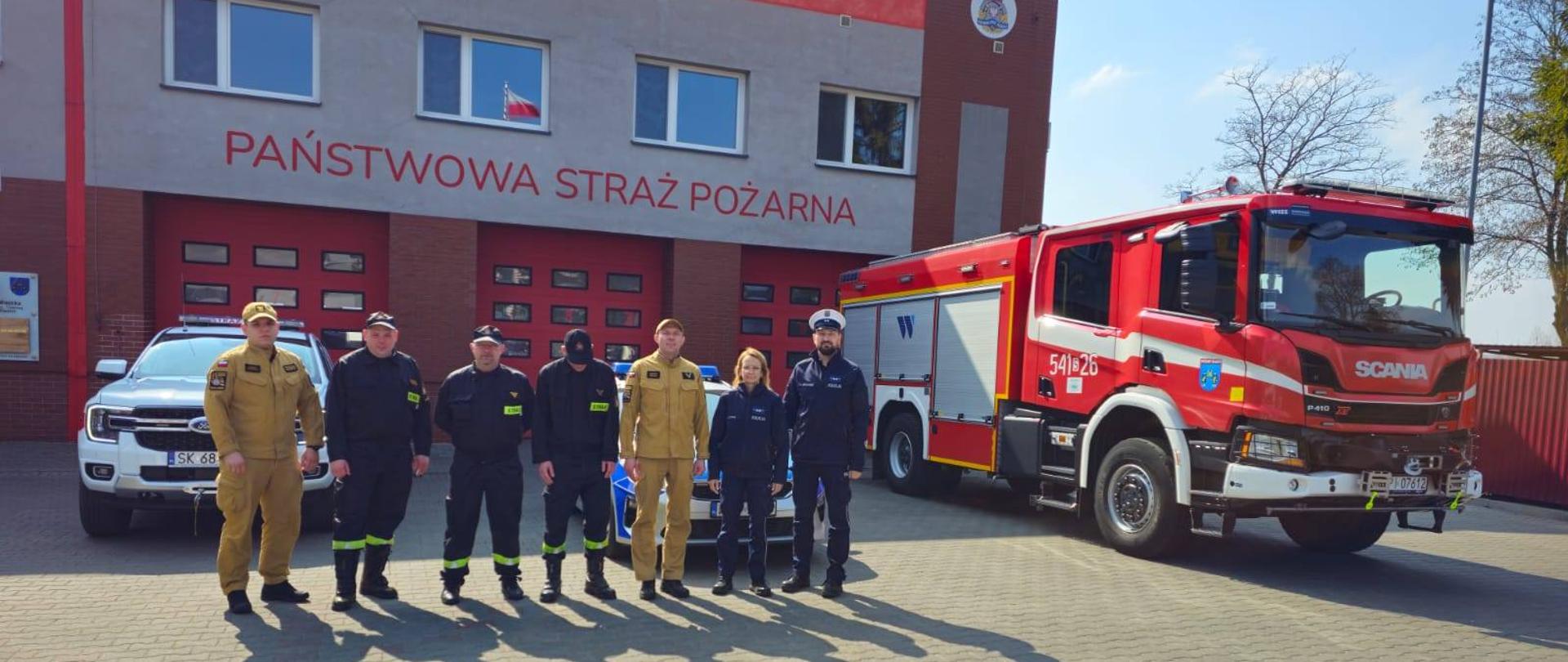 Na zdjęciu widać Komendę Miejską Państwowej Straży Pożarnej w Piekarach Śląskich, samochody, strażaków oraz policjantów