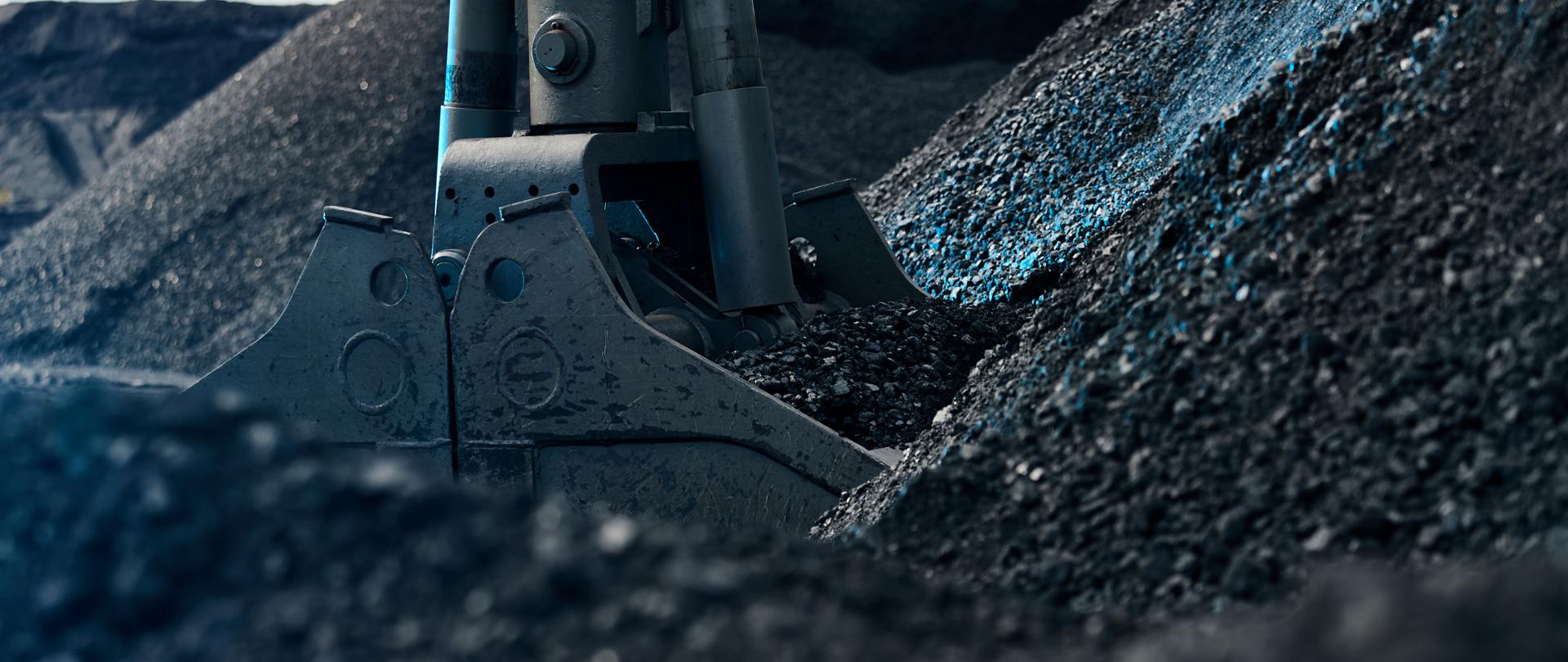 Koparka ładuje węgiel. Widoczne hałdy węgla. 