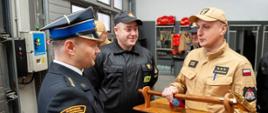 Na zdjęciu widoczny jest starszy kapitan Michał Kawałek otrzymujący od pożegnalny prezent od funkcjonariuszy z Komendy Powiatowej Państwowej Straży Pożarnej w Ostrowcu Świętokrzyskim.