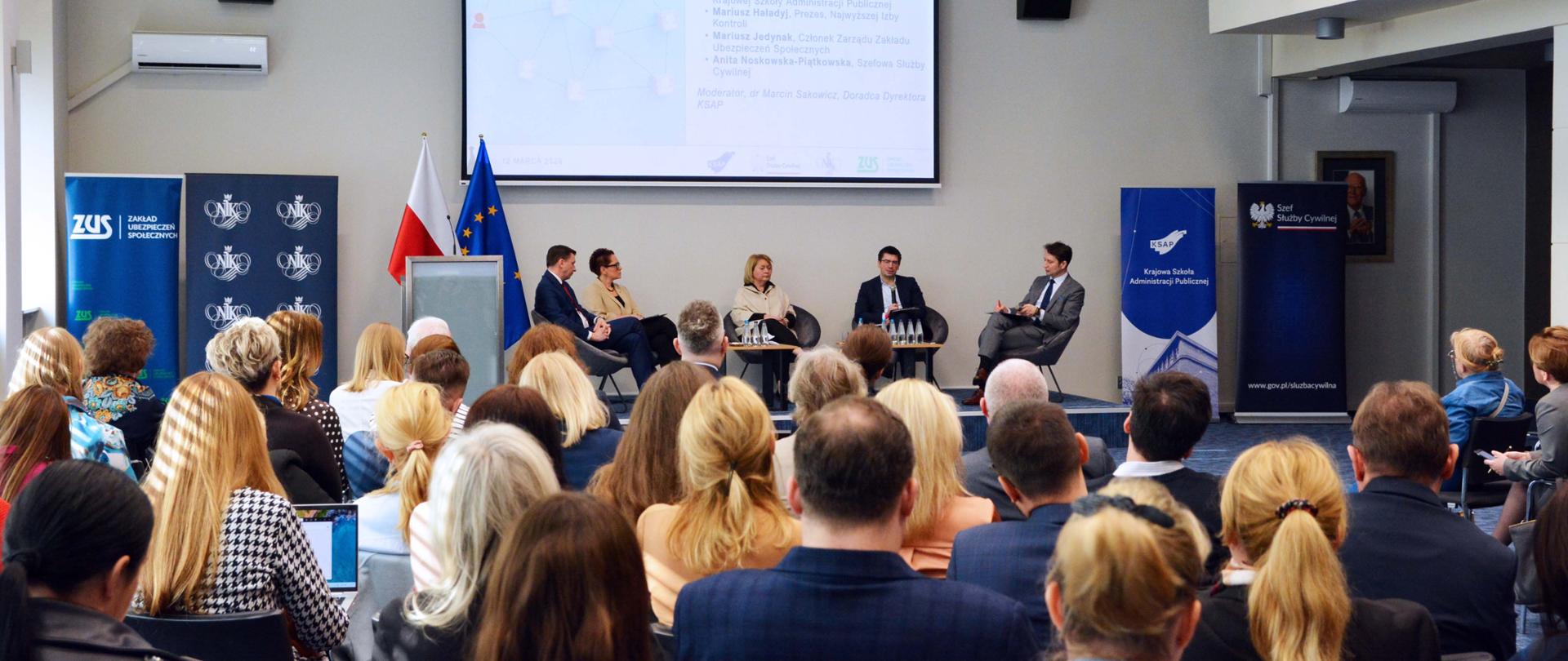 Panel dyskusyjny 5 osób na wypełnionej ludźmi auli