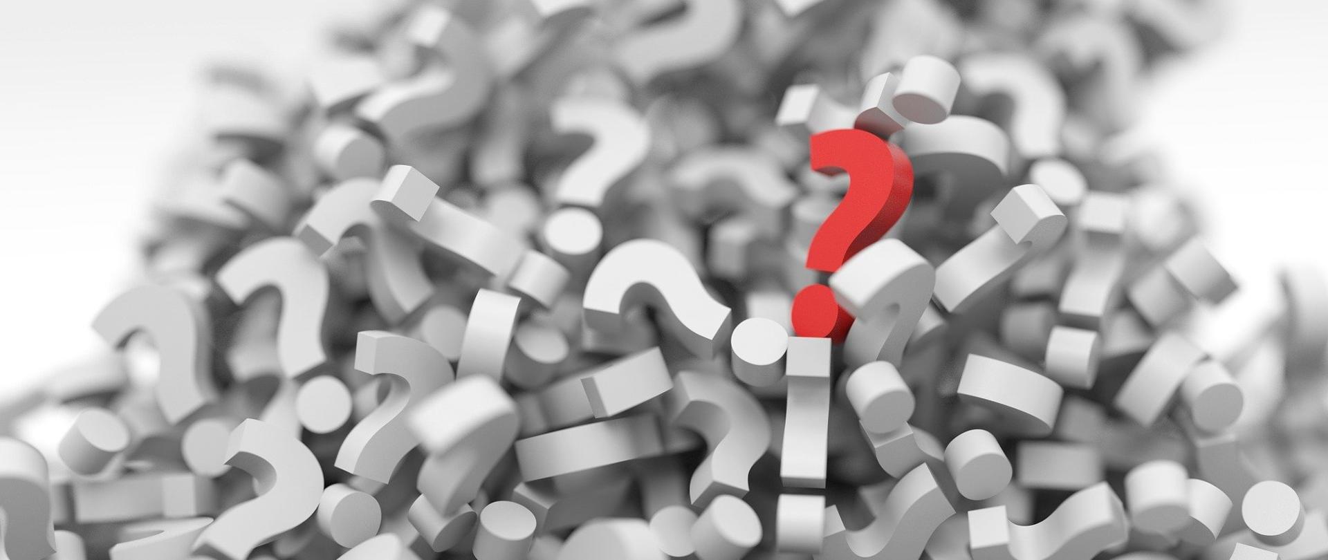 stos białych znaków zapytania z jednym czerwonym.