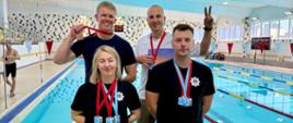 Zawodnicy, funkcjonariusze Państwowej Straży Pożarnej w stroju sportowym stoją po zdobyciu lokat i podium na Mistrzostwach Polski Służb Mundurowych w Pływaniu oraz Mistrzostwach Polski Państwowej Straży Pożarnej w Pływaniu. Zdjęcie wykonane na basenie krytym (pływalni) Akademii Policji w Szczytnie. Wspólne zdjęcie zawodników, reprezentantów Państwowej Straży Pożarnej województwa opolskiego.