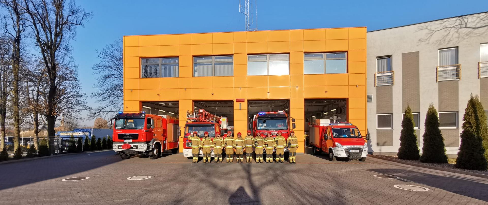GARAŻ JEDNOSTKI RATOWNICZO - GAŚNICZEJ W TLE SAMOCHODY POŻARNICZE I STRAŻACY