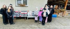 Zdjęcie grupy dziewcząt, które stoją obok zebranej karmy dla psów w puszkach dla psów z fundacji Medor