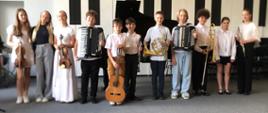 Wszyscy wykonawcy stoją ze swoimi instrumentami na scenie.