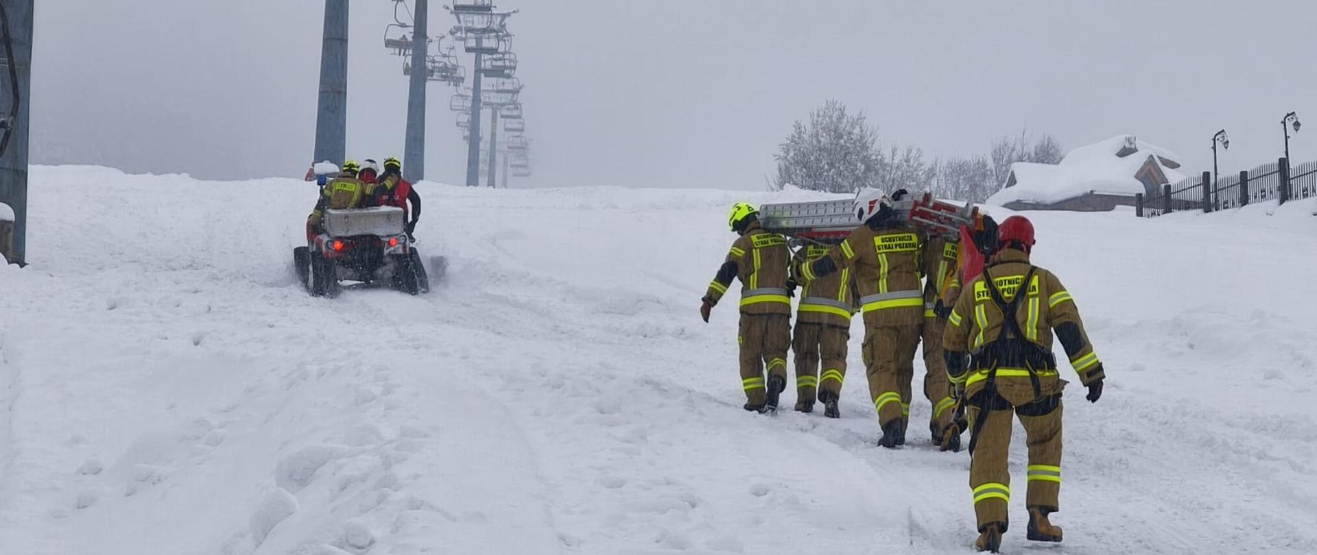 Zdjęcie przedstawia strażaków ćwiczących ewakuację poszkodowanych z wyciągu krzesełkowego