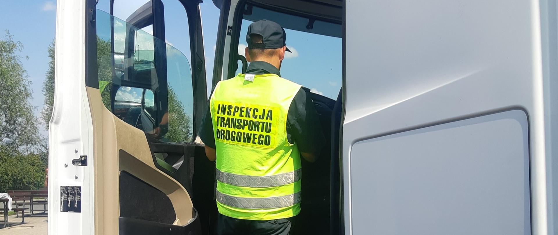 Umundurowany inspektor dolnośląskiej ITD stoi w wejściu do kabiny ciężarówki zatrzymanej do kontroli drogowej na autostradzie A4 koło Wrocławia.