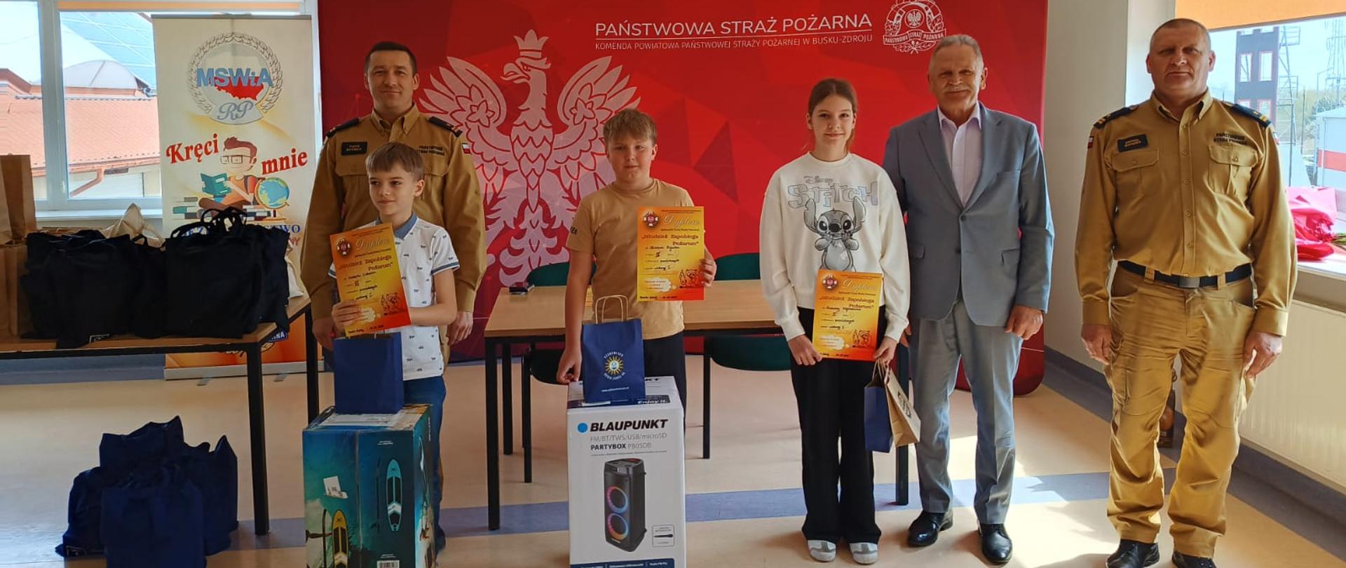 Zdjęcie przedstawia zwycięzców grupy 1 na tle baneru straży