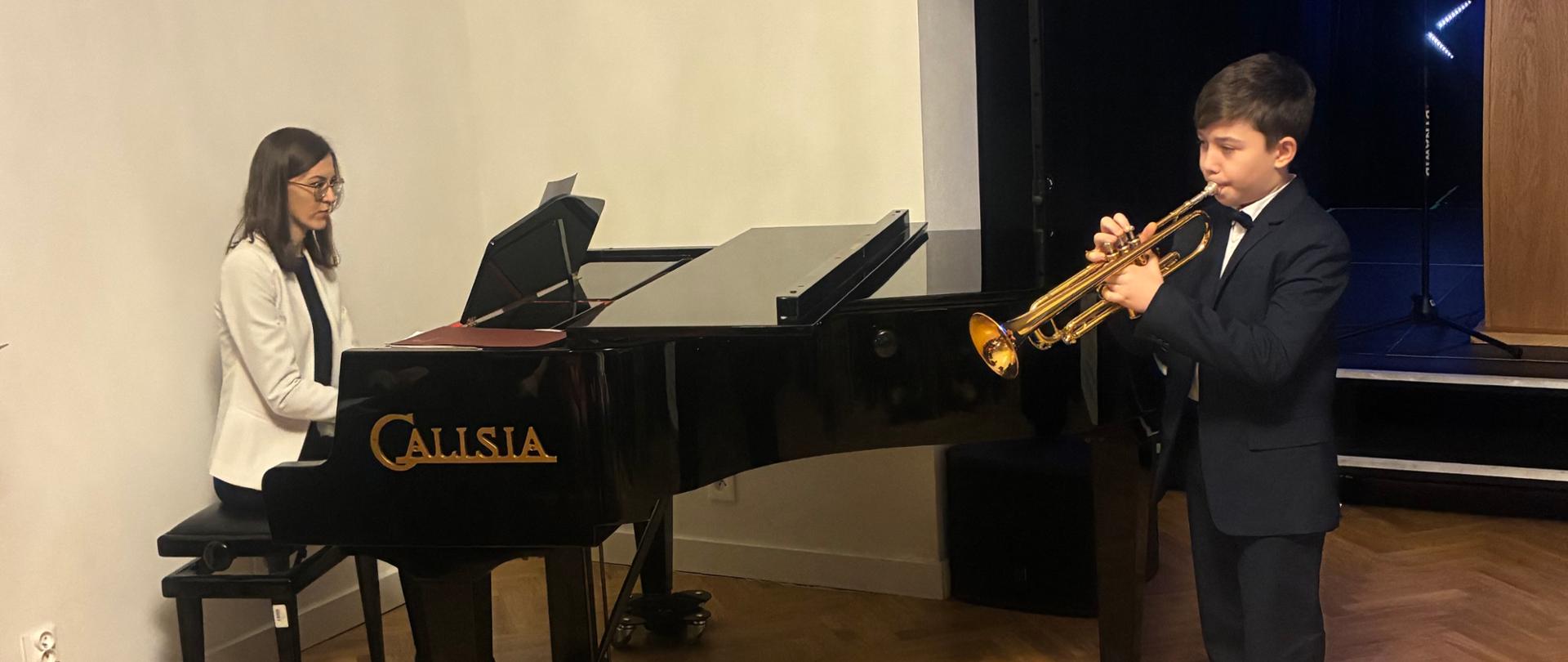 Uczeń gra na trąbce, nauczycielka na fortepianie