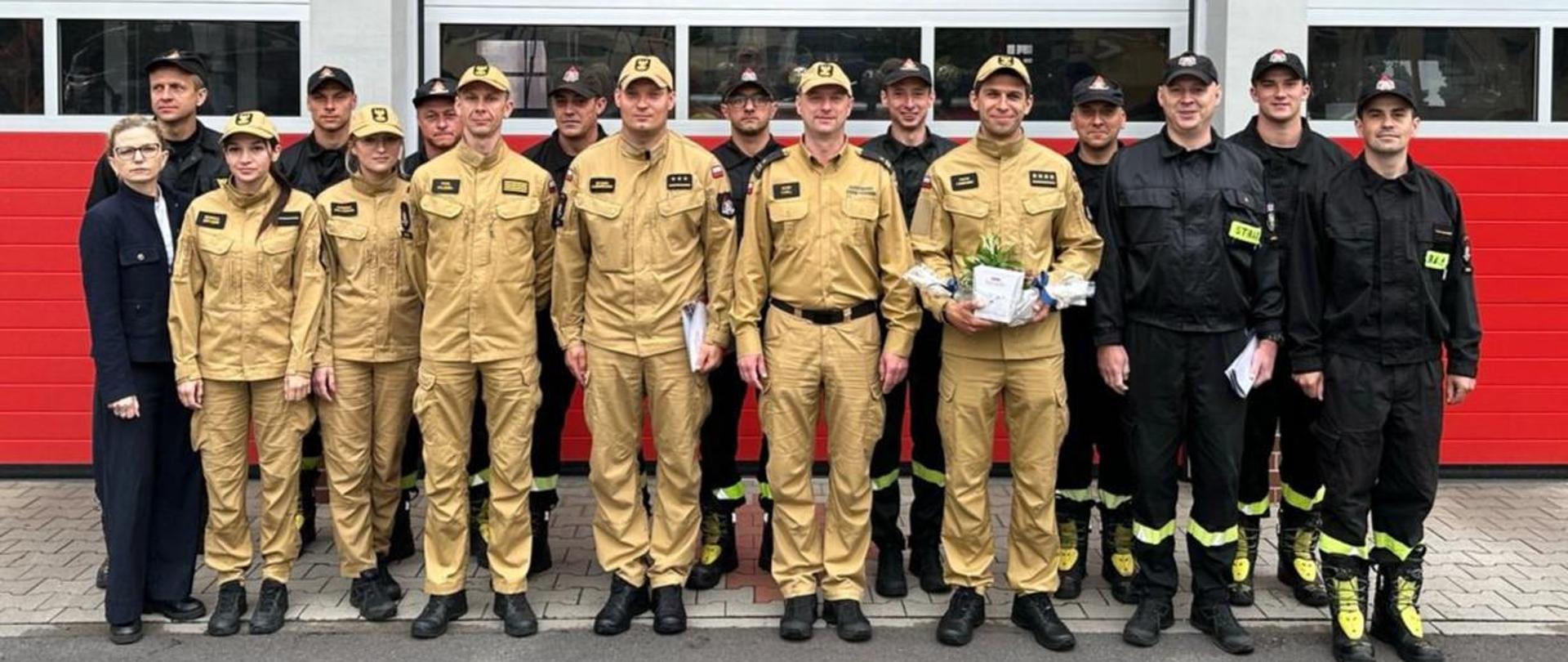 Zmiana kierownictwa Komendy Powiatowej PSP w Kościanie. Funkcjonariusze stoją w dwóch rzędach przed strażnicą, za nimi budynek Komendy.