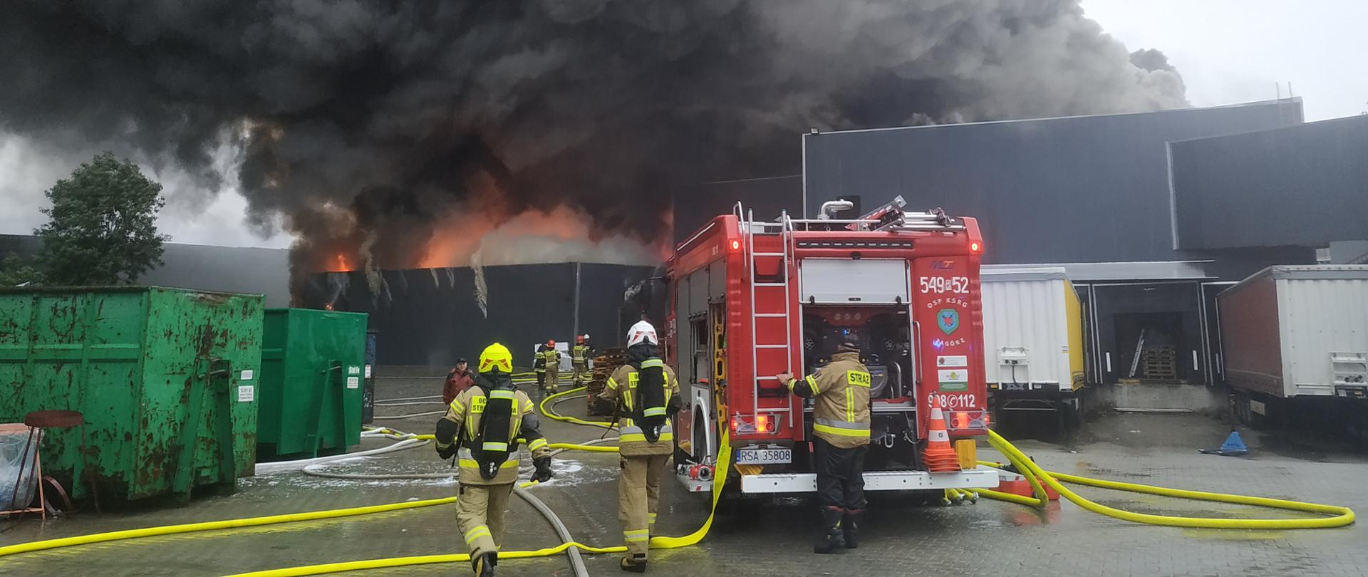 Zdjęcie przedstawia kompleks budynków firmy Ciarko - plac wewnętrzny. Na pierwszym planie strażacy prowadzacy działania gaśnicze. 