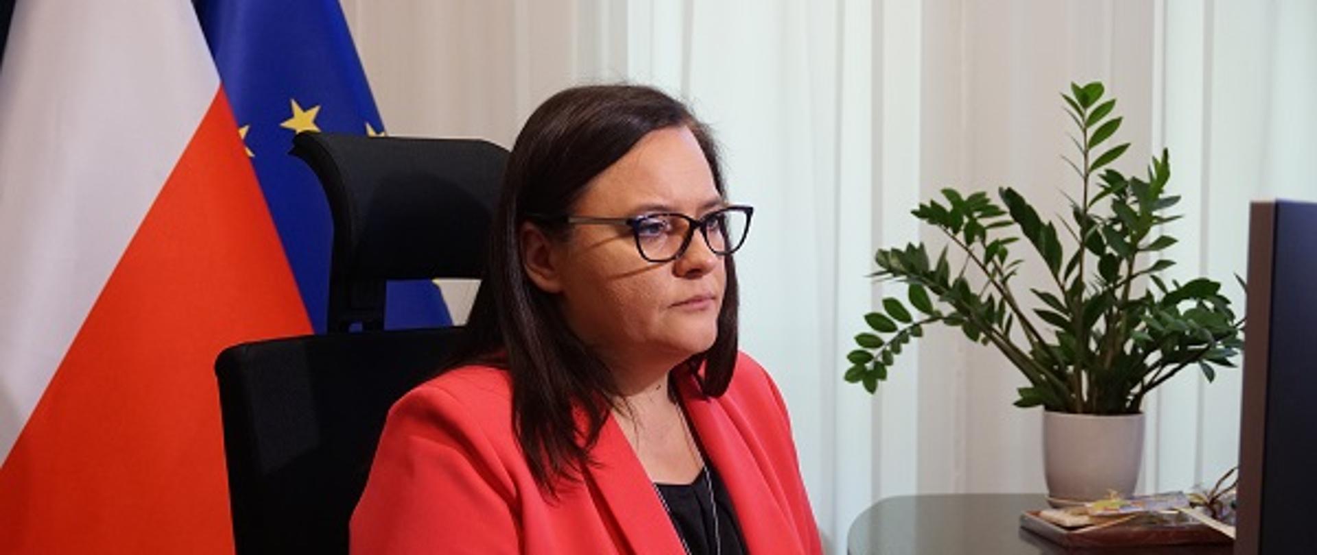 Wiceminister Jarosińska-Jedynak siedzi przy biurku, przed komputerem. 