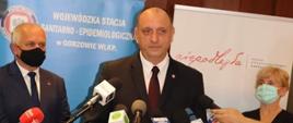 Zdjęcie przedstawia Głównego Inspektora Sanitarnego Krzysztofa Saczkę stojącego przed mikrofonami, z jego prawej strony stoi Wojewoda Lubuski Władysław Dajczak, natomiast z lewej Lubuski Państwowy Wojewódzki Inspektor Sanitarny Dorota Konaszczuk.