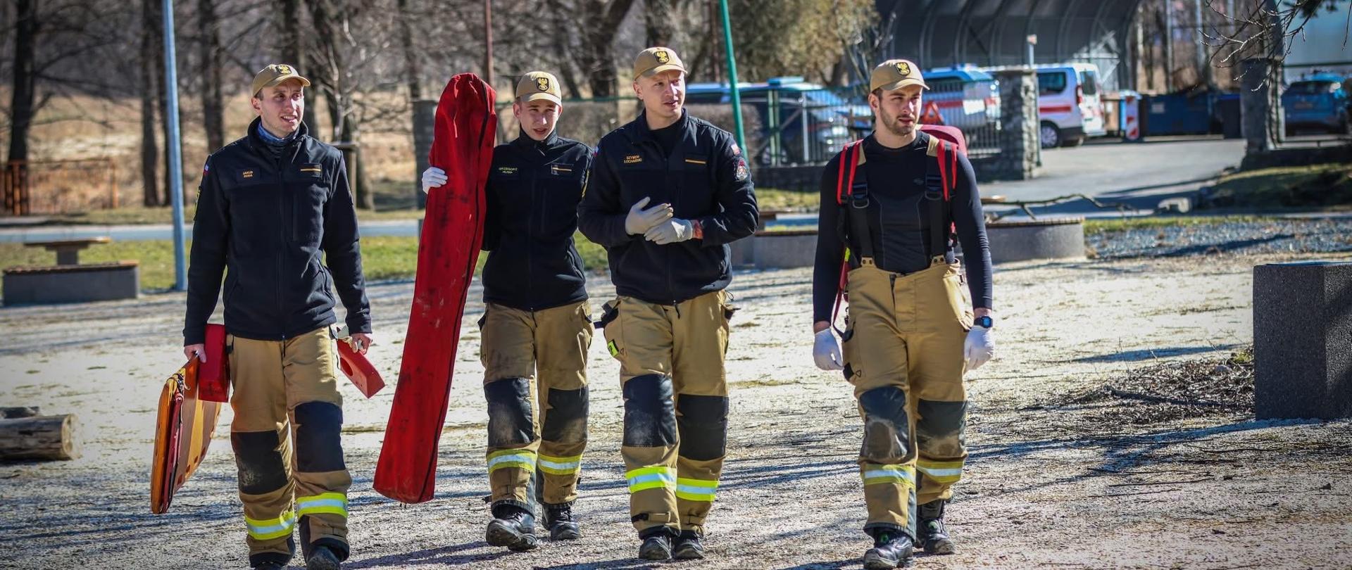 Czterej strażacy komendy powiatowej straży pożarnej w Trzebnicy, na zdjęciu grupowym. Strażacy trzymają sprzęt ratowniczy.