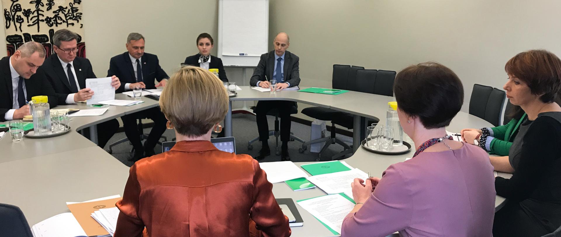 Sala spotkań, ludzie siedzą przy sześciokątnym stole.