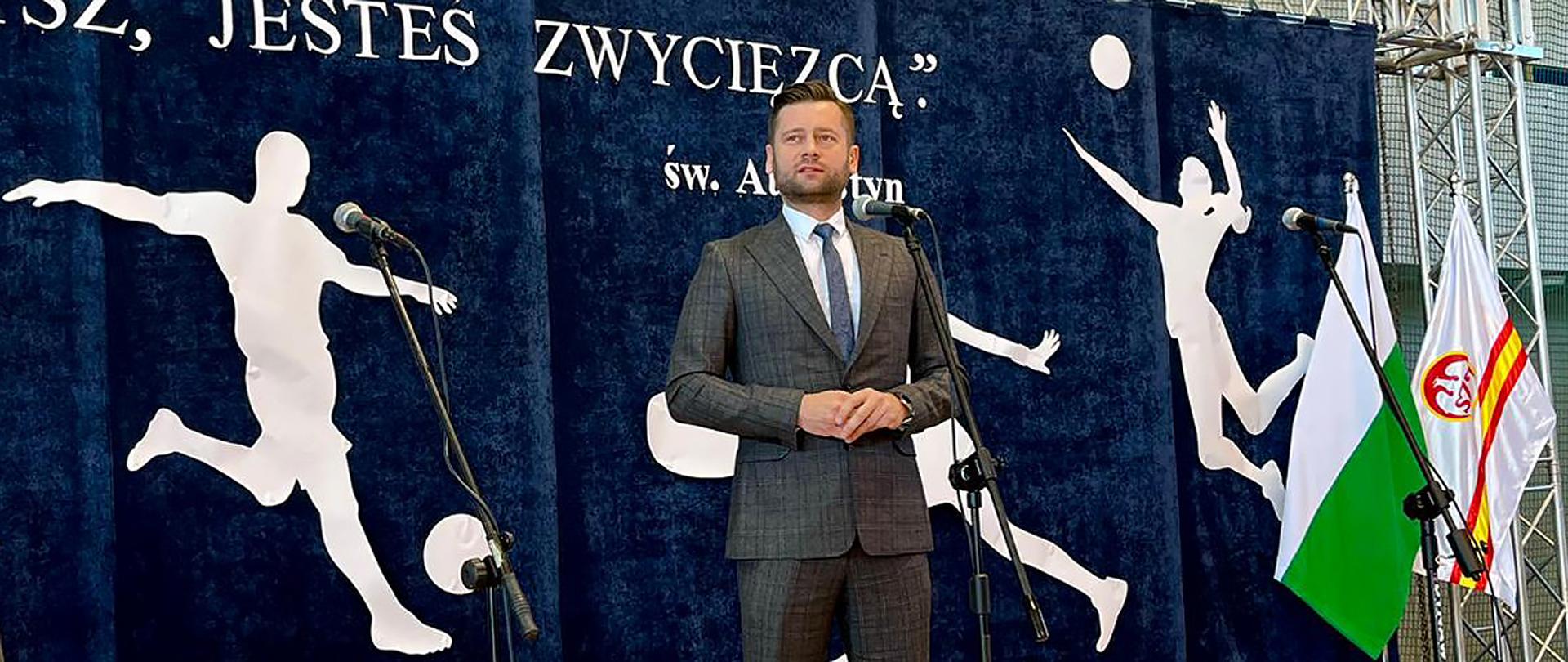 Minister sportu i turystyki Kamil Bortniczuk uczestniczył w uroczystym podsumowaniu współzawodnictwa sportowego uczniów chełmskich szkół. Na zdjęciu minister przemawia do mikrofonu, w tle napis "Jesteś zwycięzcą"