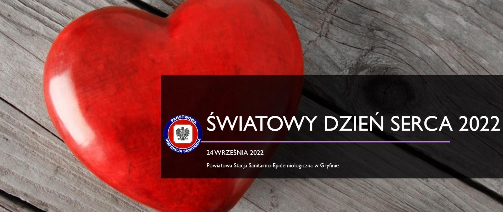 Czerwone sztuczne serce na tle drewnianej deski. Pośrodku logo inspekcji sanitarnej oraz napis Światowy Dzień serca 2022