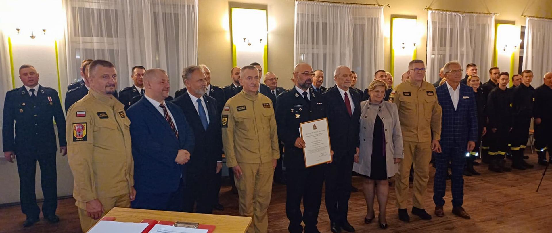 druhowie strażacy politycy i samorządowcy pozują do zdjęcia w sali