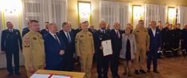 druhowie strażacy politycy i samorządowcy pozują do zdjęcia w sali