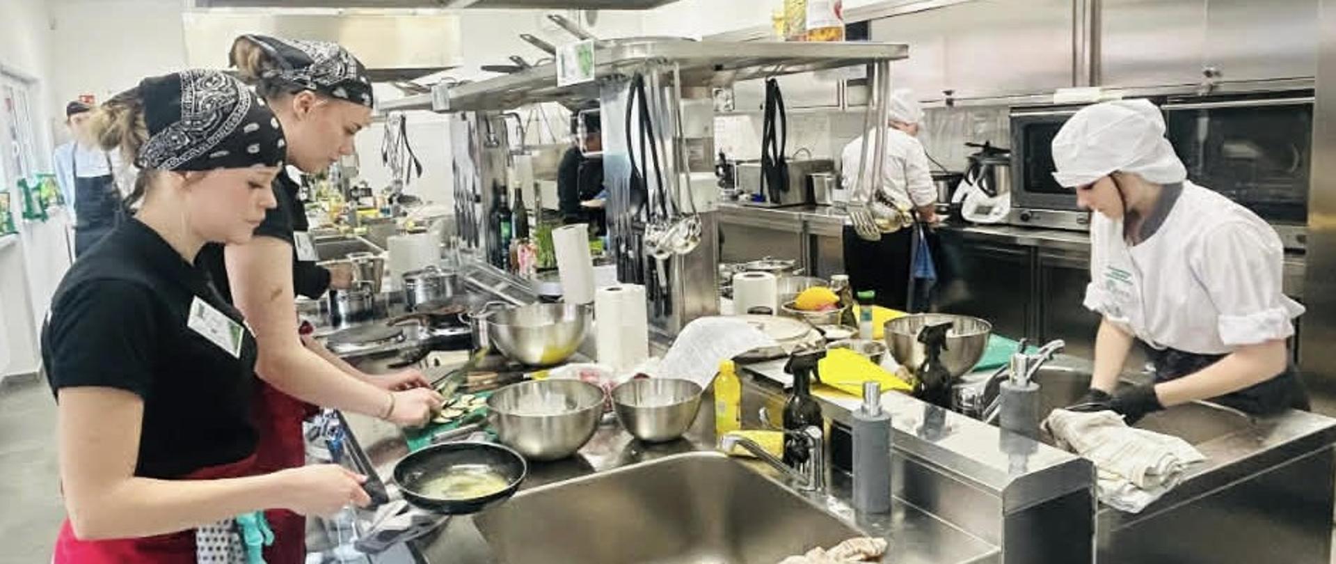 Uczestnicy konkursu w kuchni podczas wykonywania dań