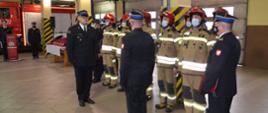 Zdjęcie przedstawia starszego brygadiera Zbigniewa Łyszkowicza Zastępcę Komendanta Wojewódzkiego Państwowej Straży Pożarnej w Łodzi oraz dowódcę uroczystości i komendanta powiatowego państwowej straży pożarnej w wieluniu podczas przyjmowania meldunku, w tle samochód pożarniczy i strażacy w strojach bojowych