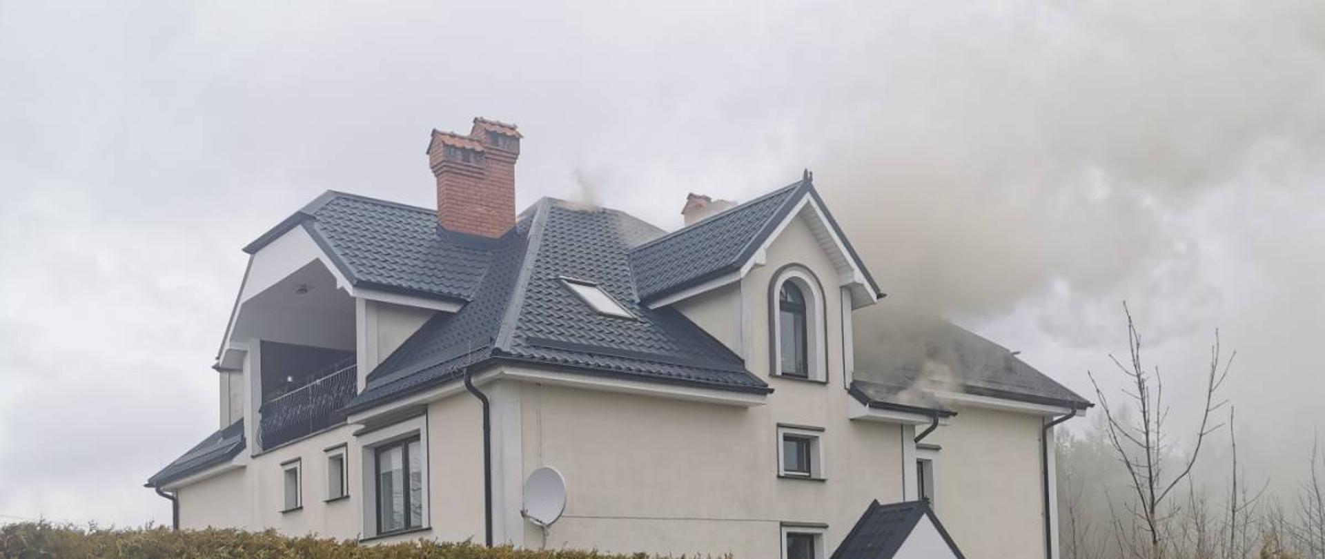 Kłęby dymu unoszące się nad dachem budynku, w którym doszło do pożaru.