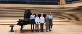 Uczniowie klasy Pani Edyty Suchanek z nauczycielem przy fortepianie na scenie sali koncertowej PSM