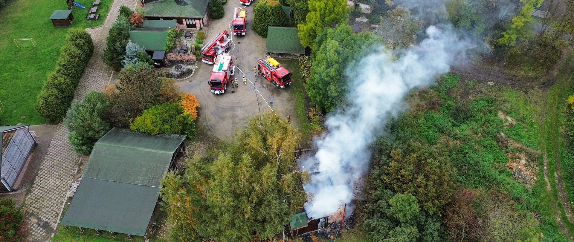 zdjęcie z lotu ptaka przedstawiające pożar budynku letniskowego i pojazdy pożarnicze 