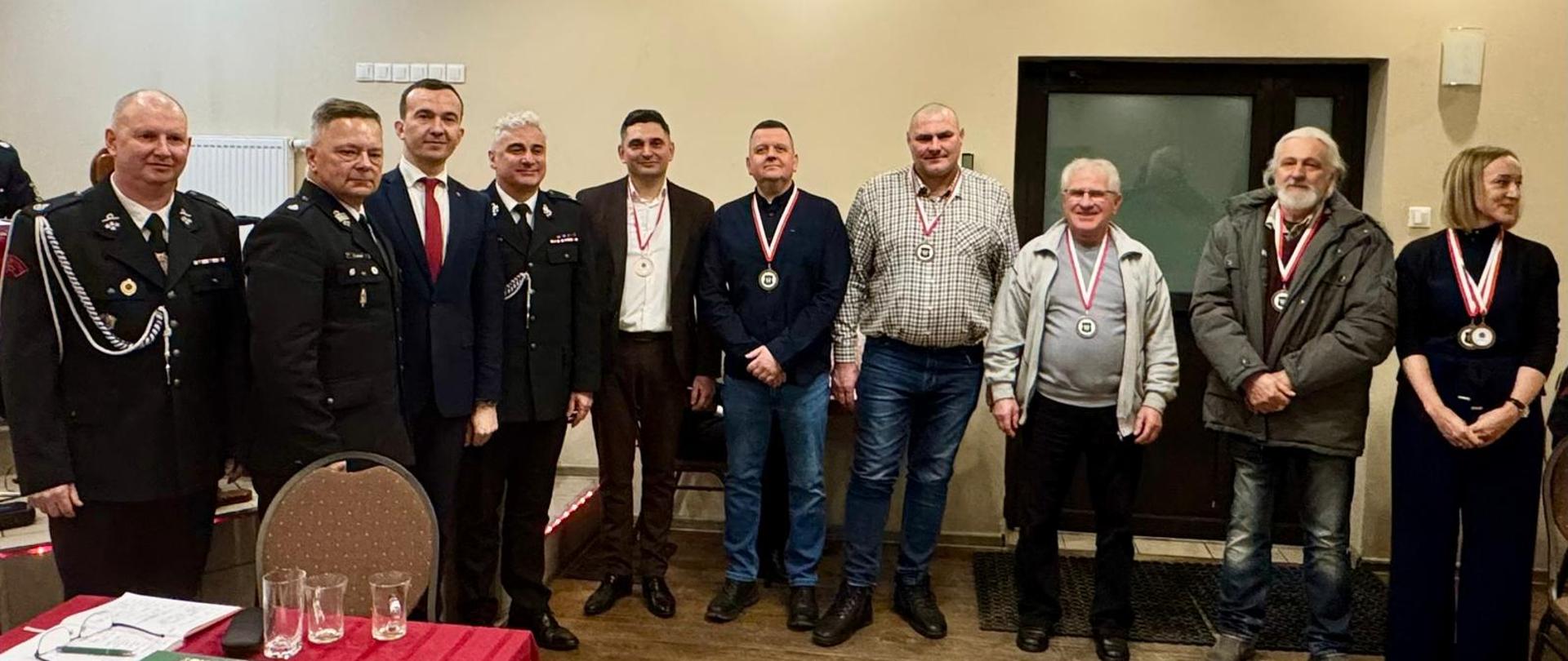 Grupa ludzi stoi obok siebie, uśmiechają się 